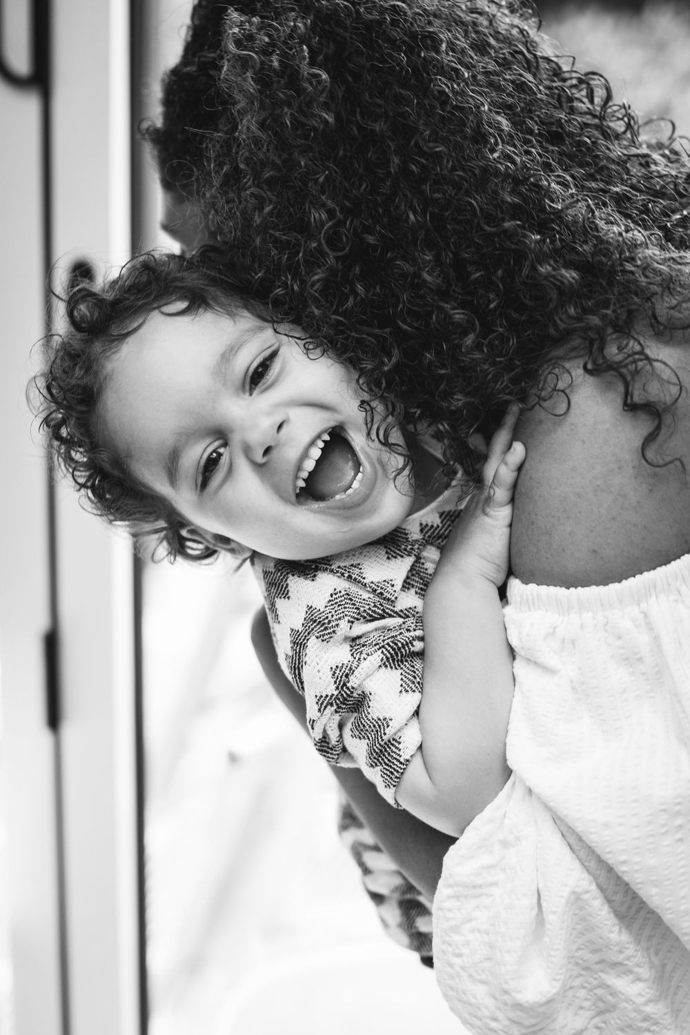 Black and white portrait capturing pure joy and laughter during a playful moment.