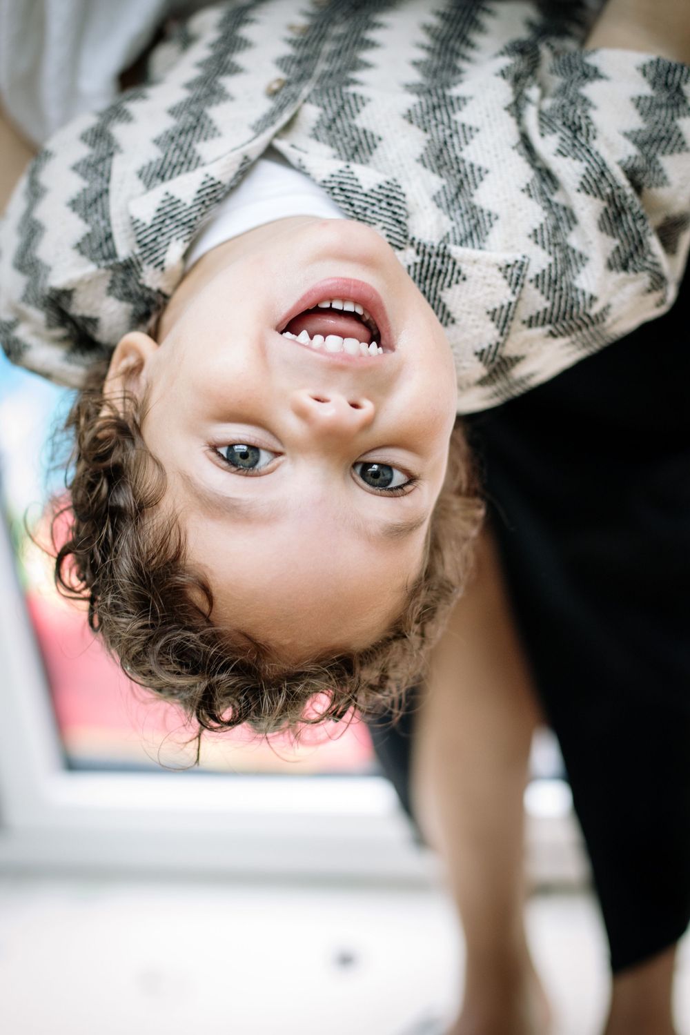 Close-up portrait of a child wearing chevron pattern clothing looking down at camera with pure joy.