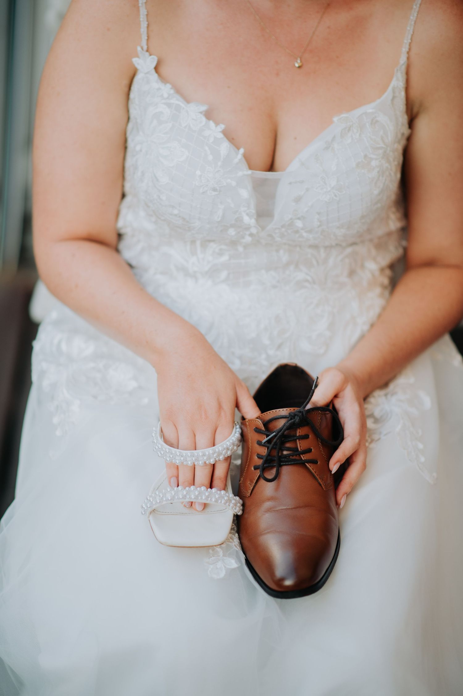 Wedding detail shot showing a white lace dress and brown leather dress shoe.