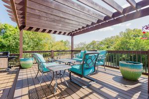 A modern outdoor patio features a wooden pergola with turquoise lounge chairs and seating arrangements for relaxation.