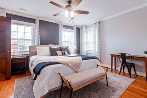 Secondary bedroom with ceiling fan, neutral walls and hardwood floors in residential home.
