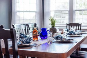Elegant dining table set with blue and white place settings, glassware, and decorative blue pitcher.
