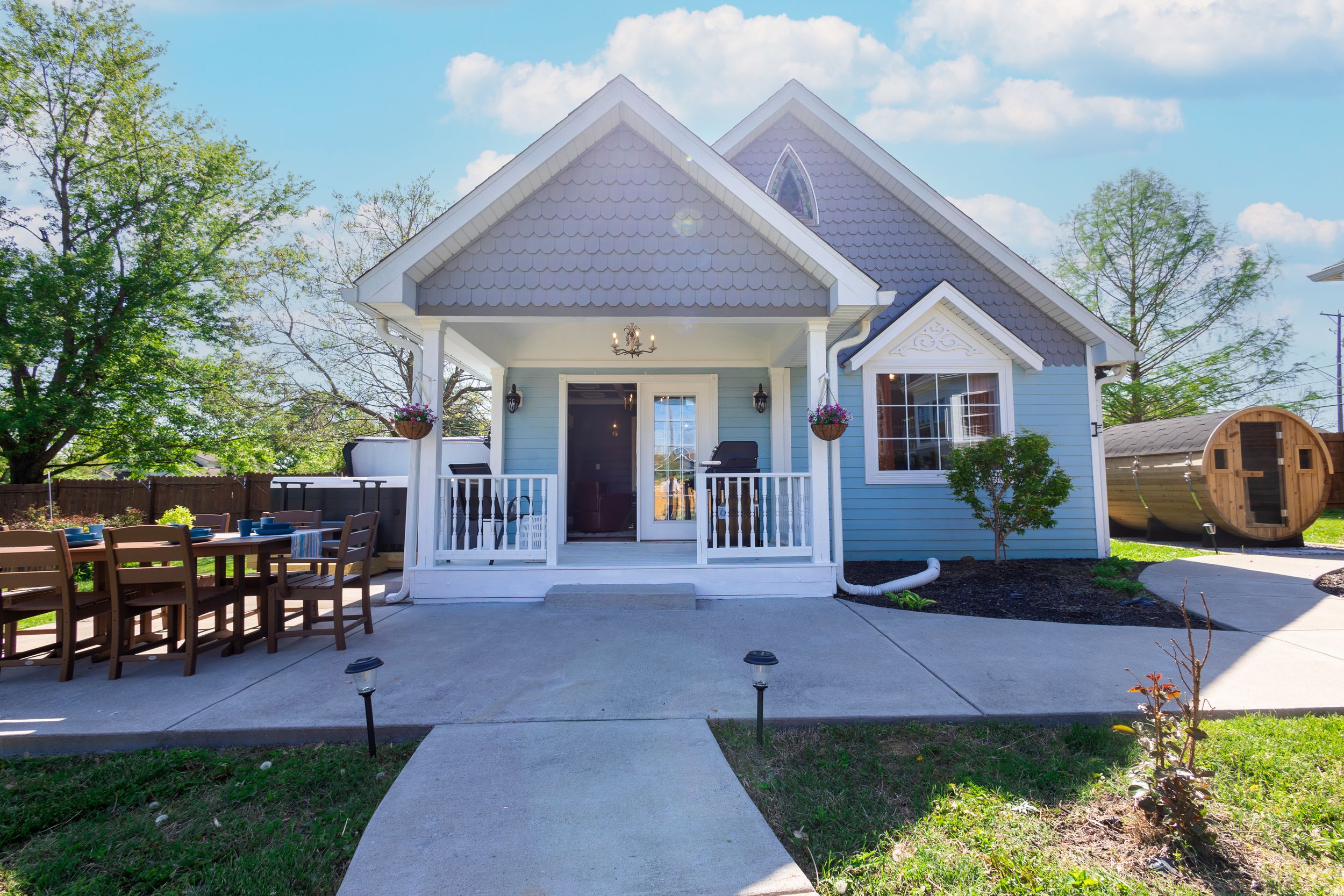 Charming gray cottage-style home with white trim, front porch, and outdoor dining area.