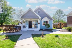 White residential houses with landscaped yards and driveways line a suburban neighborhood street.