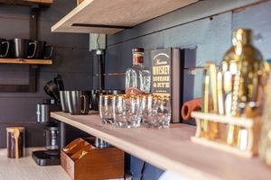 Bar shelf displaying whiskey bottles, glasses, and golden decorative elements.