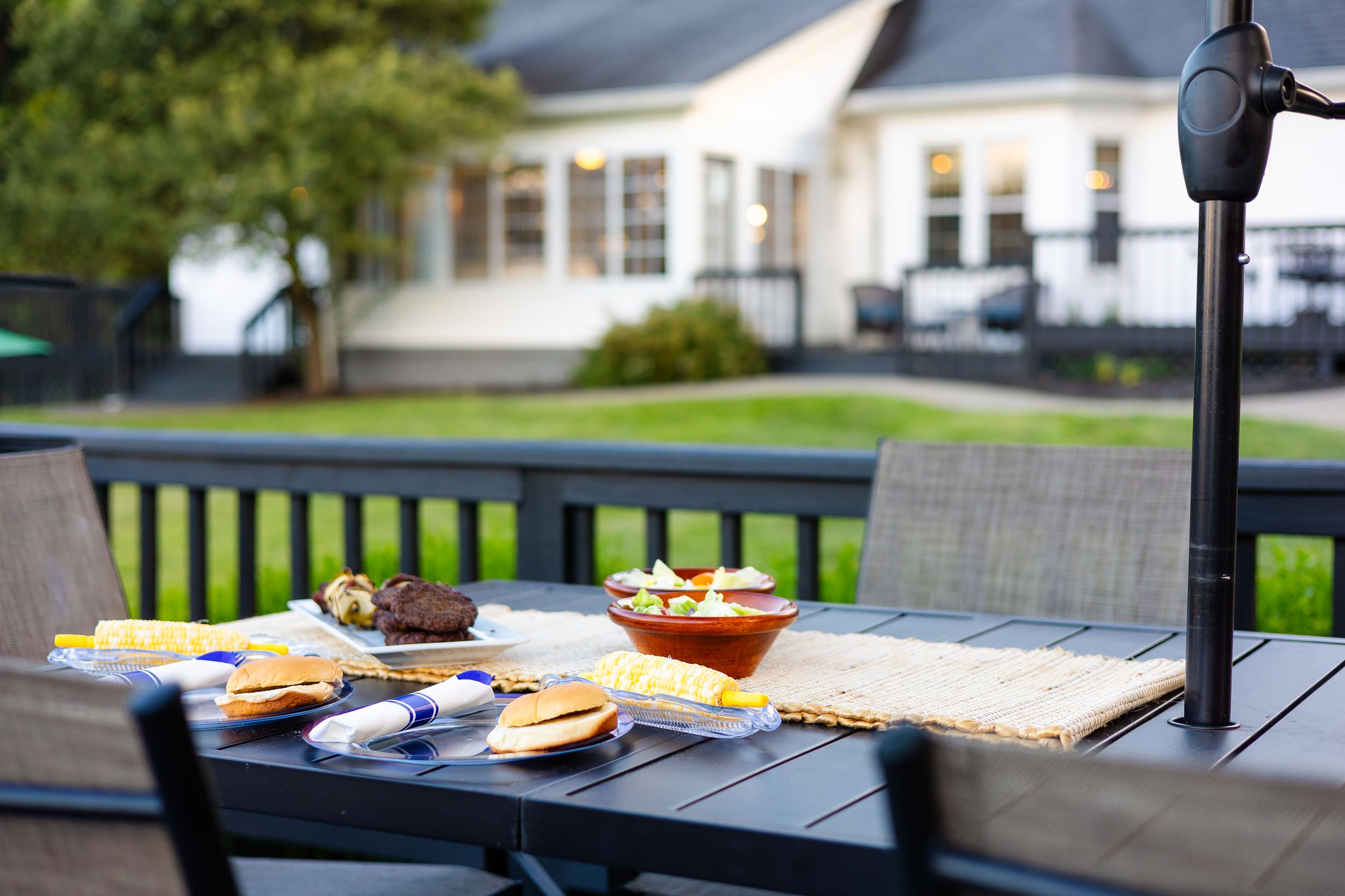 Row of wooden picnic tables with benches arranged outdoors on a sunny patio or deck area.