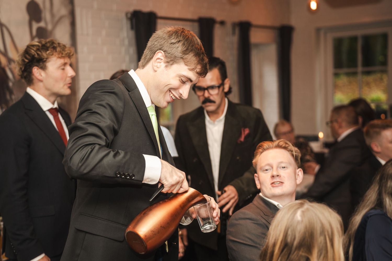 Guests in formal attire socialize and mingle at an elegant indoor reception event.
