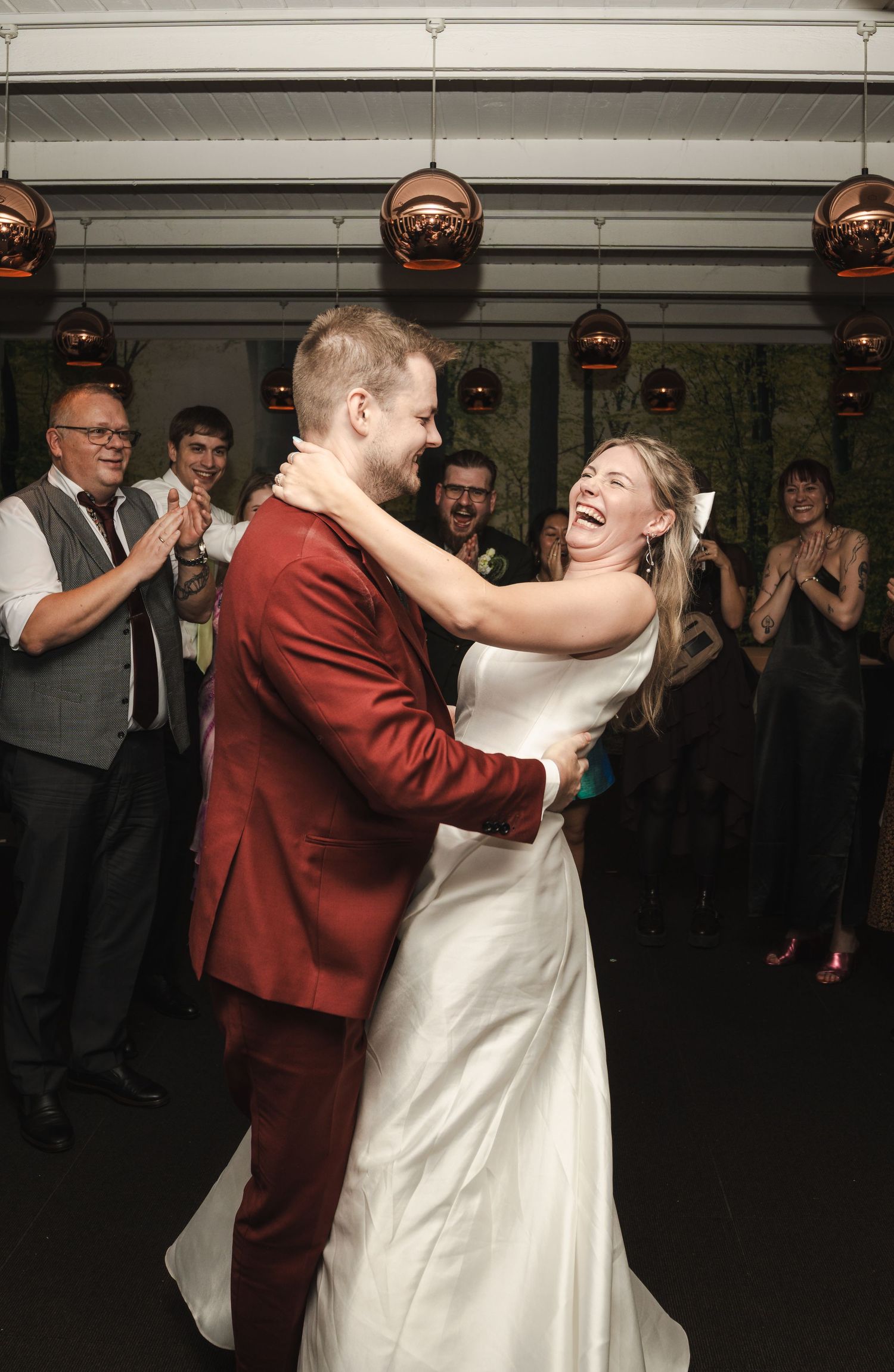 A couple shares a joyful dance together at their wedding reception in a dimly lit venue.