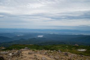 Panoramic mountain vista with rolling hills and valleys stretching to the horizon under cloudy skies.