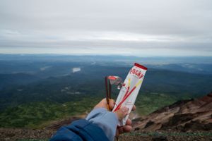 Mountain summit view with trail markers and expansive valley views in the distance.