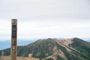 Mountain ridgeline stretches across the horizon with wooden trail markers in the foreground.