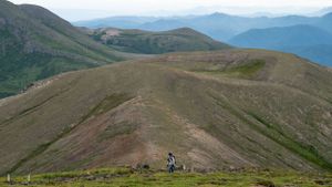 Hiking trail winding along mountain ridgeline with expansive valley views.