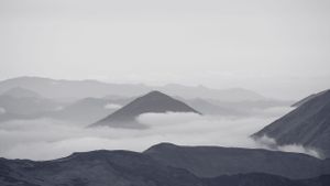 Misty mountain peaks emerging through low-lying clouds in a moody landscape.