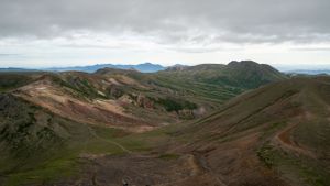 Dramatic mountain landscape with winding trails and cloudy skies stretching across the horizon.