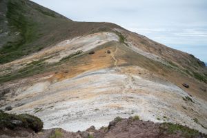 Panoramic view of a steep mountain trail winding through mineral-stained volcanic terrain.