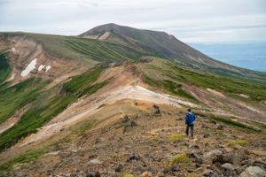 Mountain hiking trail winds along a rocky ridge with dramatic valley views.
