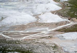 Aerial view of geothermal hot springs and mineral deposits in a mountainous landscape.