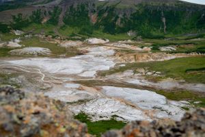 Panoramic view of mountain valleys with geothermal features and green vegetation.