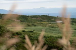 Rolling green hills and mountains under cloudy skies with distant peaks.
