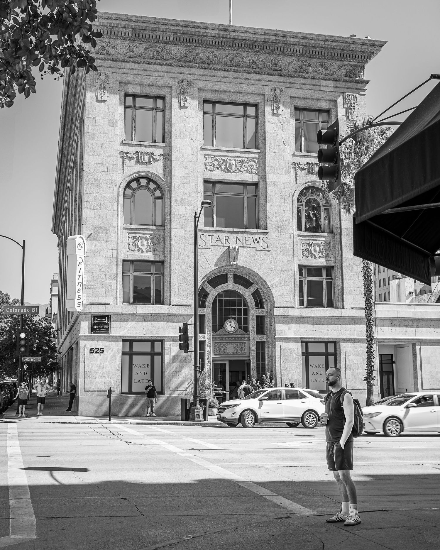 Black and white photo of a historic three-story neoclassical building with an ornate stone facade and parked cars on an urban street.