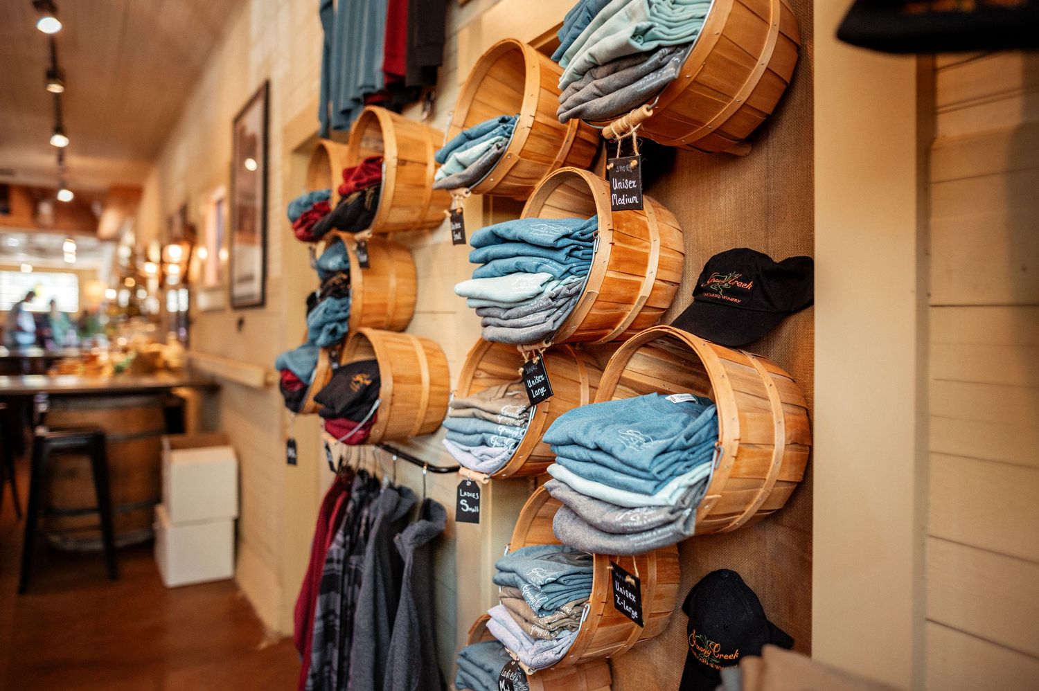 Neatly folded blue jeans displayed in wooden barrel-style shelving units on retail store wall.