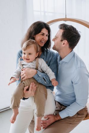 Happy family playing and laughing together against a bright white wall with natural lighting.