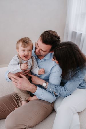 Joyful family moment sharing laughter while relaxing together on a cozy white couch.
