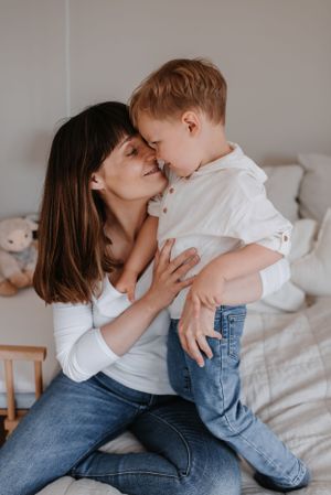 Tender moment of affection shared between parent and child on a comfortable bed.