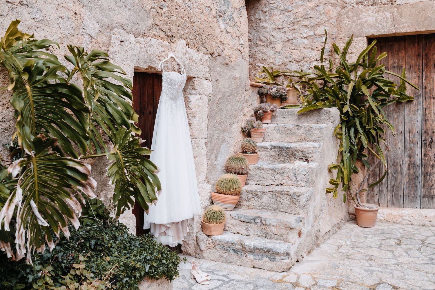 Im Innenhof der Finca Xiclati auf Mallorca befindet sich eine alte Steintreppe, die rustikale Tür ist mit einem weißen Brautkleid geschmückt