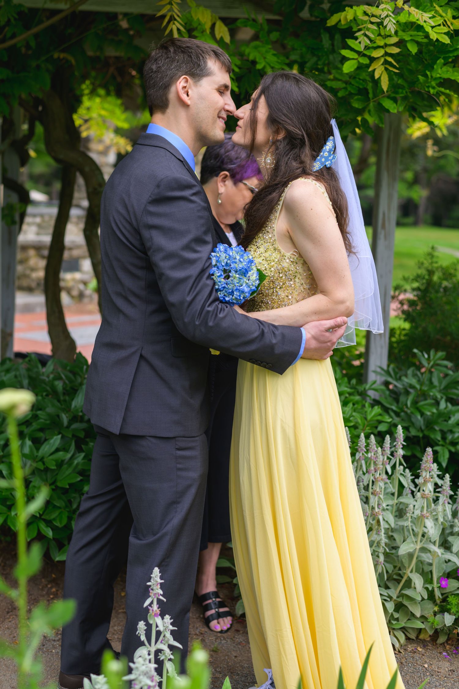 A wedding couple looking into each other's eyes in an embrace before their first kiss.