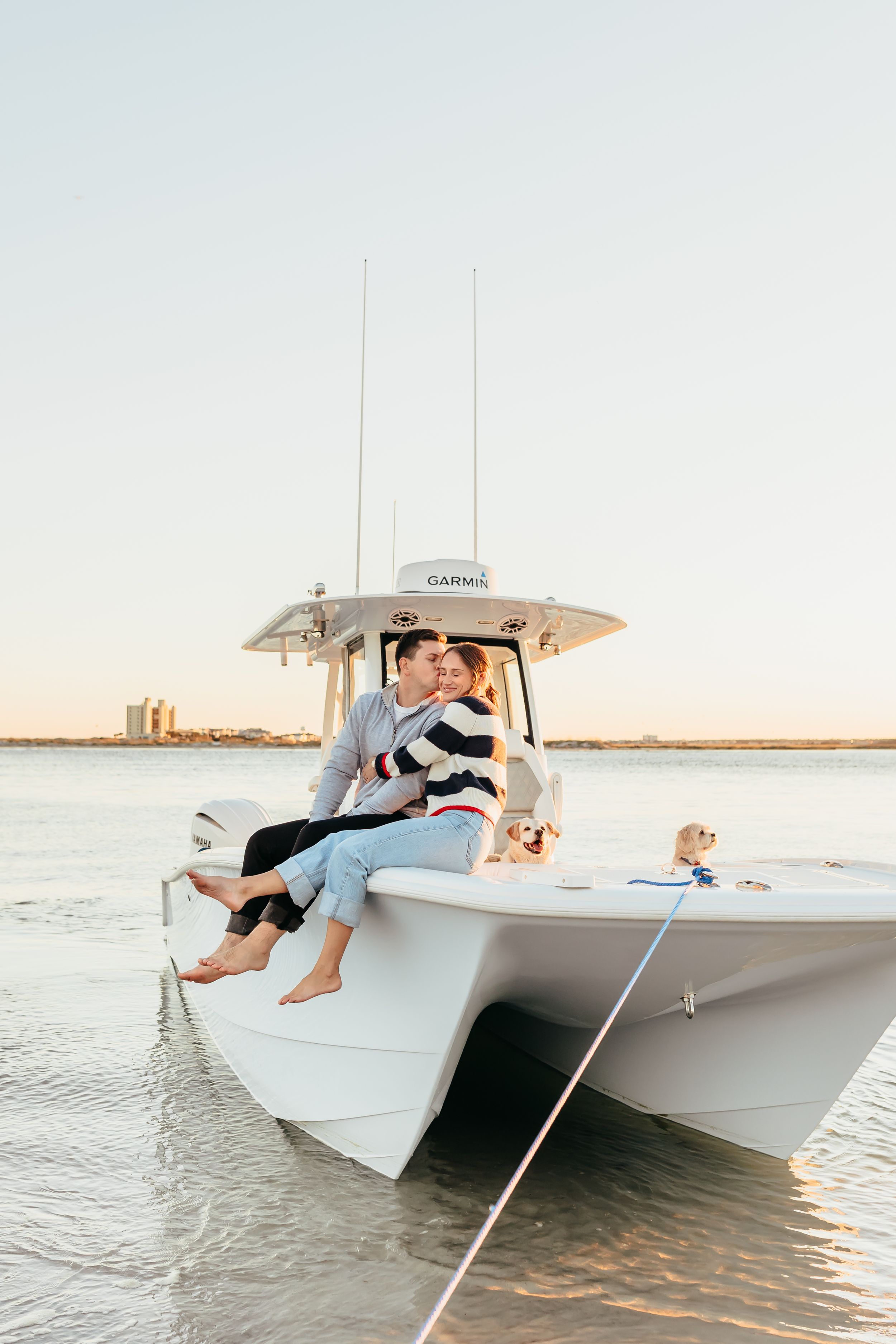 A couple enjoys a romantic sunset boat ride on a white center console vessel in calm coastal waters.