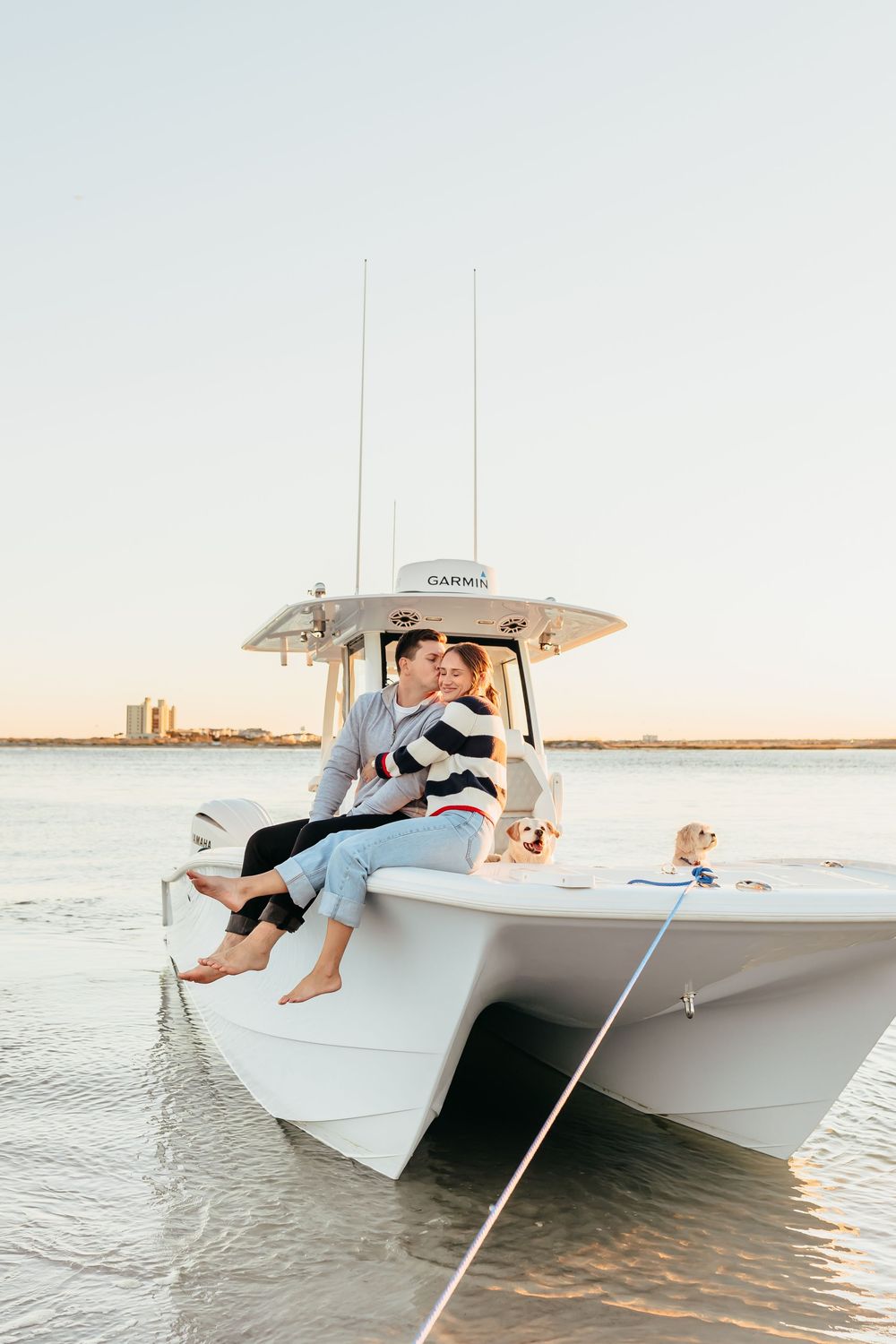A couple enjoys a romantic sunset boat ride on a white center console vessel in calm coastal waters.