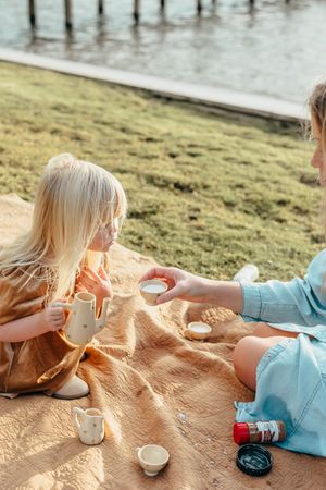 Two people sitting on a blanket having a picnic with drinks at sunset.