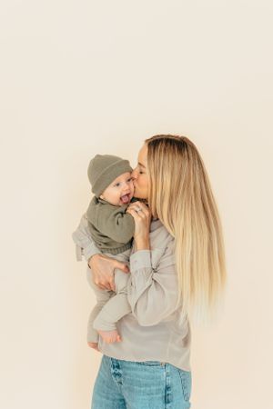 Mother and baby dressed in coordinating gray outfits share an intimate moment against a light background.