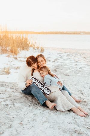 Intimate family moment captured on a beach during golden hour.