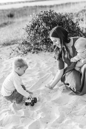 A sequence of black and white photos shows a child and adult exploring in sand at the beach.