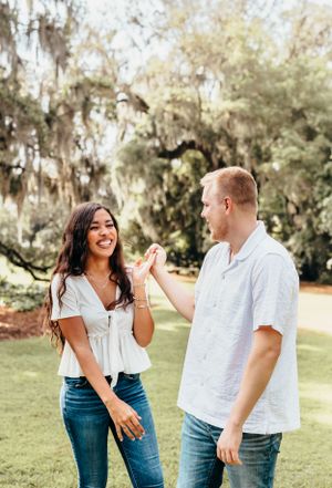 A couple shares laughs while walking together in a park setting.