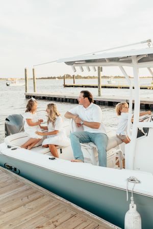 A group of people relax together on a white boat deck during a sunny day on the water.