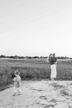 A black and white vintage photograph showing two people standing in a sandy area near a grassy field.