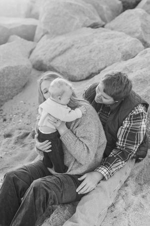 A sequence of black and white photos showing two people in plaid shirts resting together on rocky terrain.