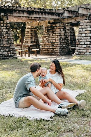 Family sits together on blanket enjoying Greenfield Lake Park in Wilmington North Carolina on sunny afternoon.