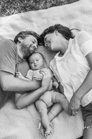 A touching black and white photo sequence shows parents and baby napping together on a textured blanket. Wilmington NC. Greenfield Lake