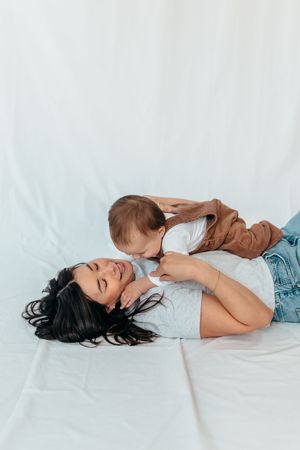A person lies on white bedding wearing casual attire in a sequence of relaxed reclining poses.