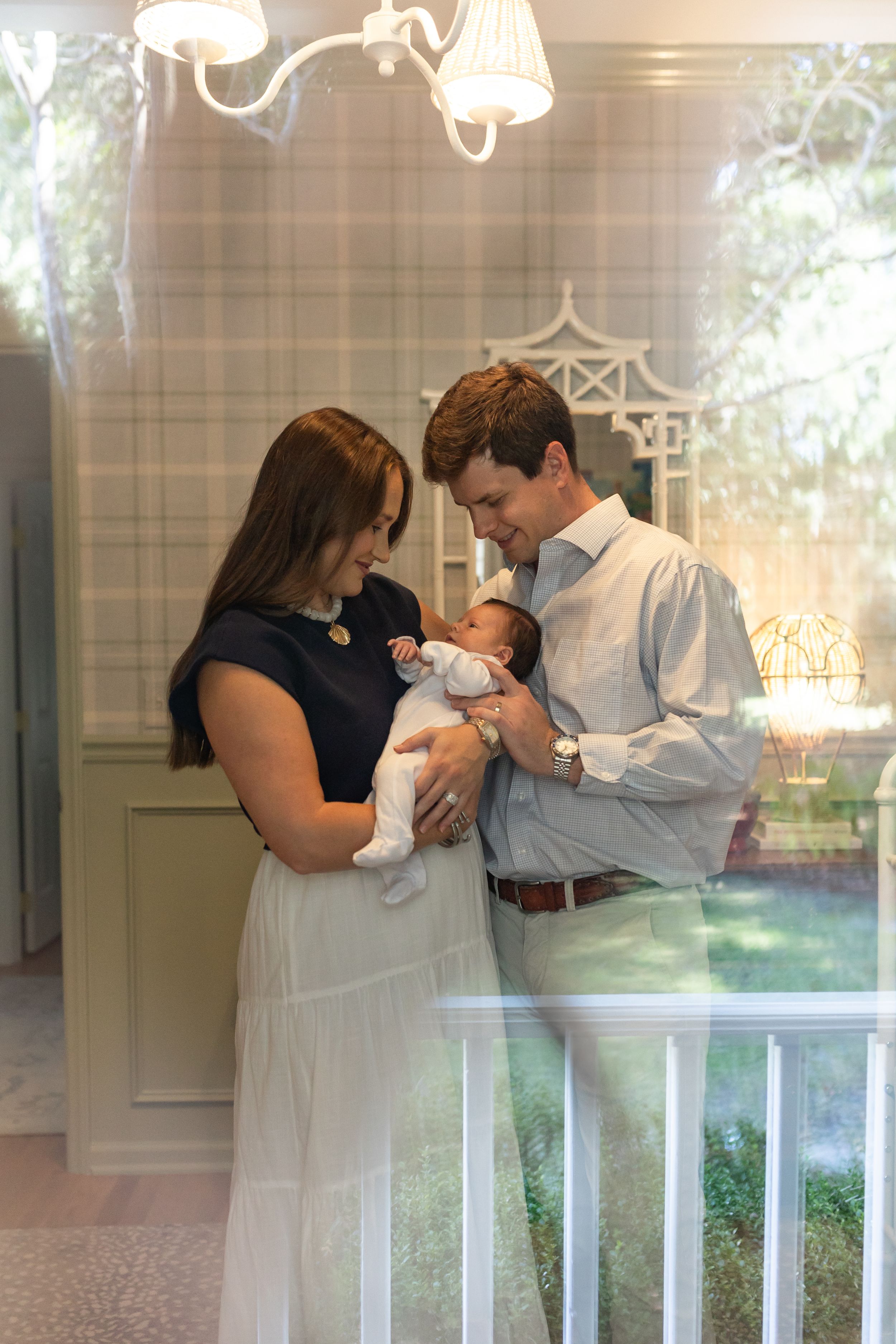 New parents lovingly gaze at their newborn baby in an elegantly decorated nursery room.