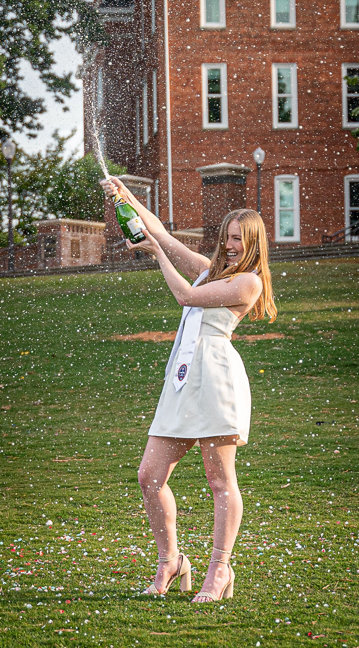 Clemson Graduate with bottle of champagne on Bowman Field with Tillman in background, Clemson South Carolina