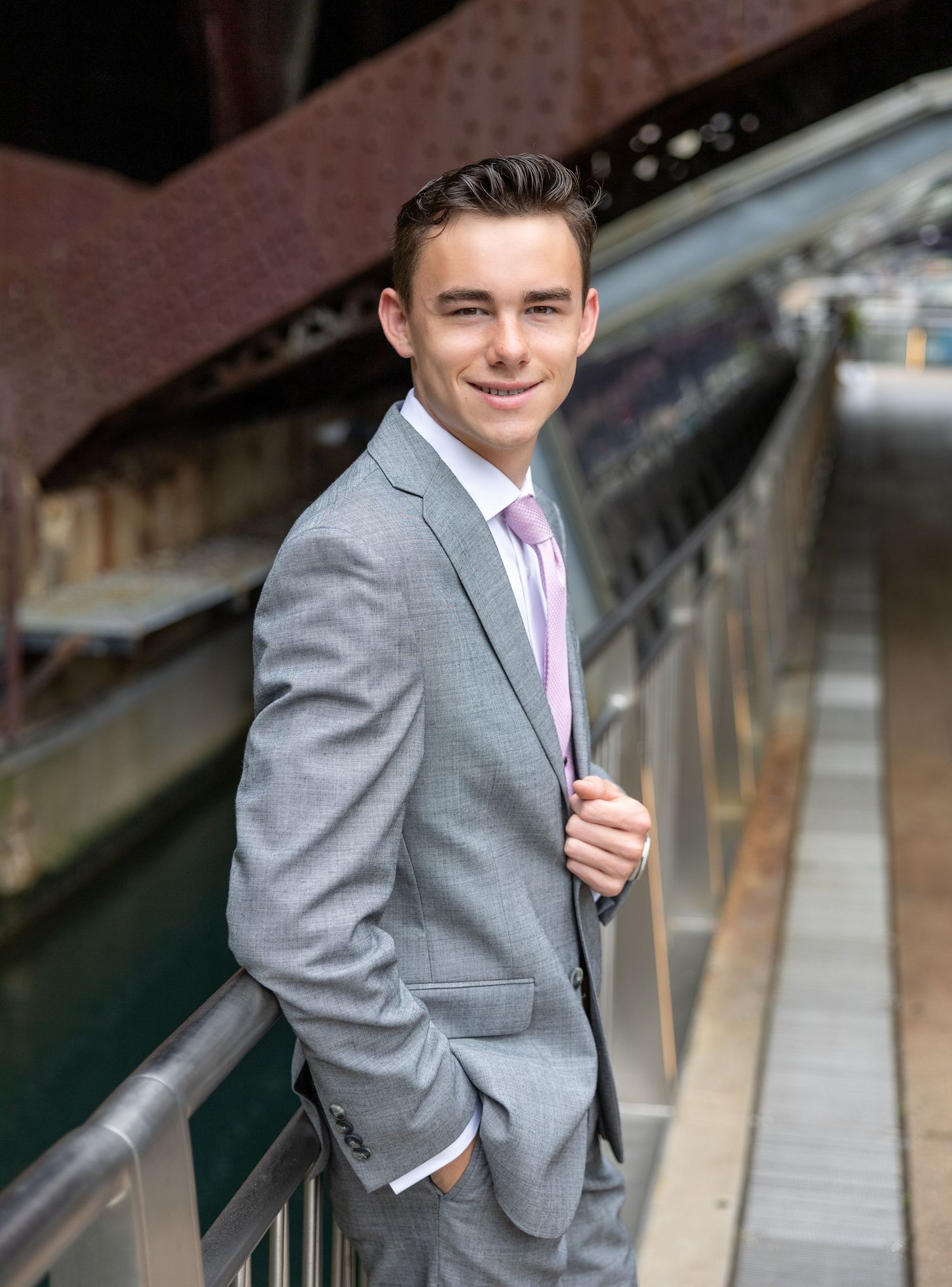 Professional portrait on bridge wearing gray suit and pink tie.