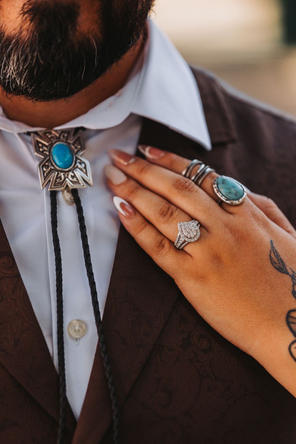 Close-up of turquoise bolo tie and rings with western wedding styling.