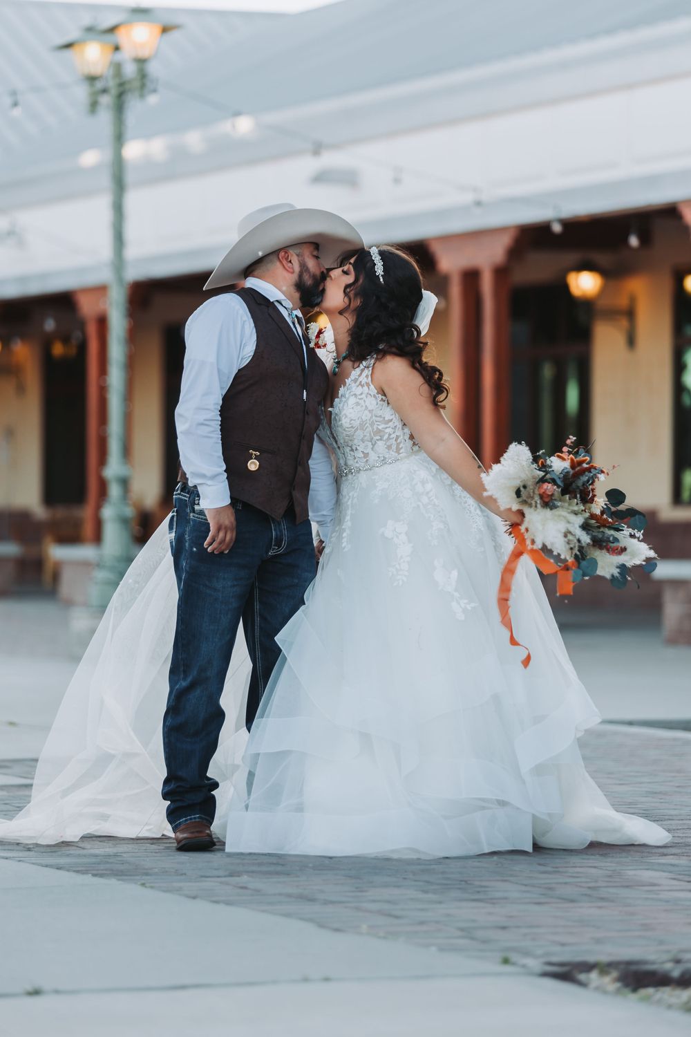 Romantic wedding couple embrace in western-themed attire.
