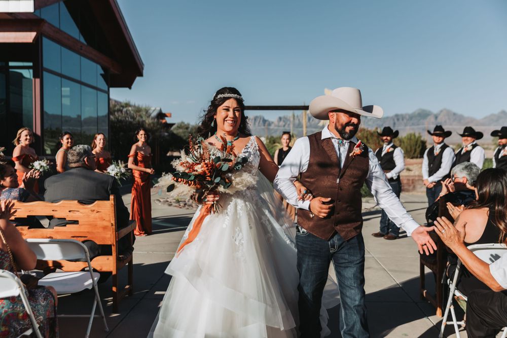 A western-themed outdoor wedding celebration with guests seated on rustic wooden chairs.