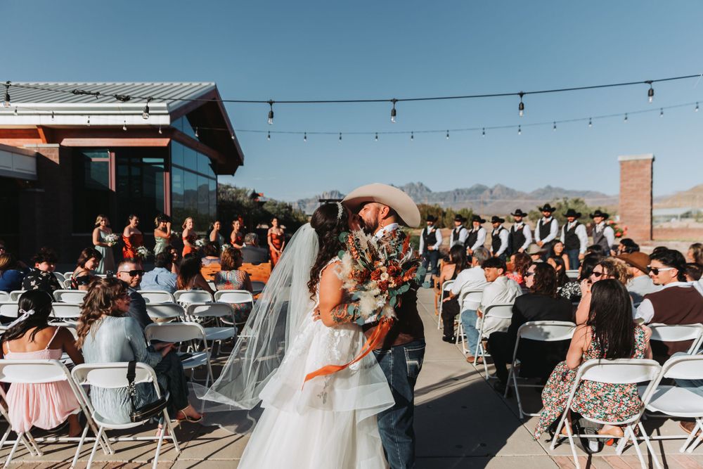 Wedding guests seated at outdoor reception with string lights and mountain views.
